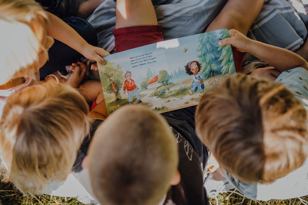 Vier Kinder die in dem Buch Schwimm, kleines Boot lesen