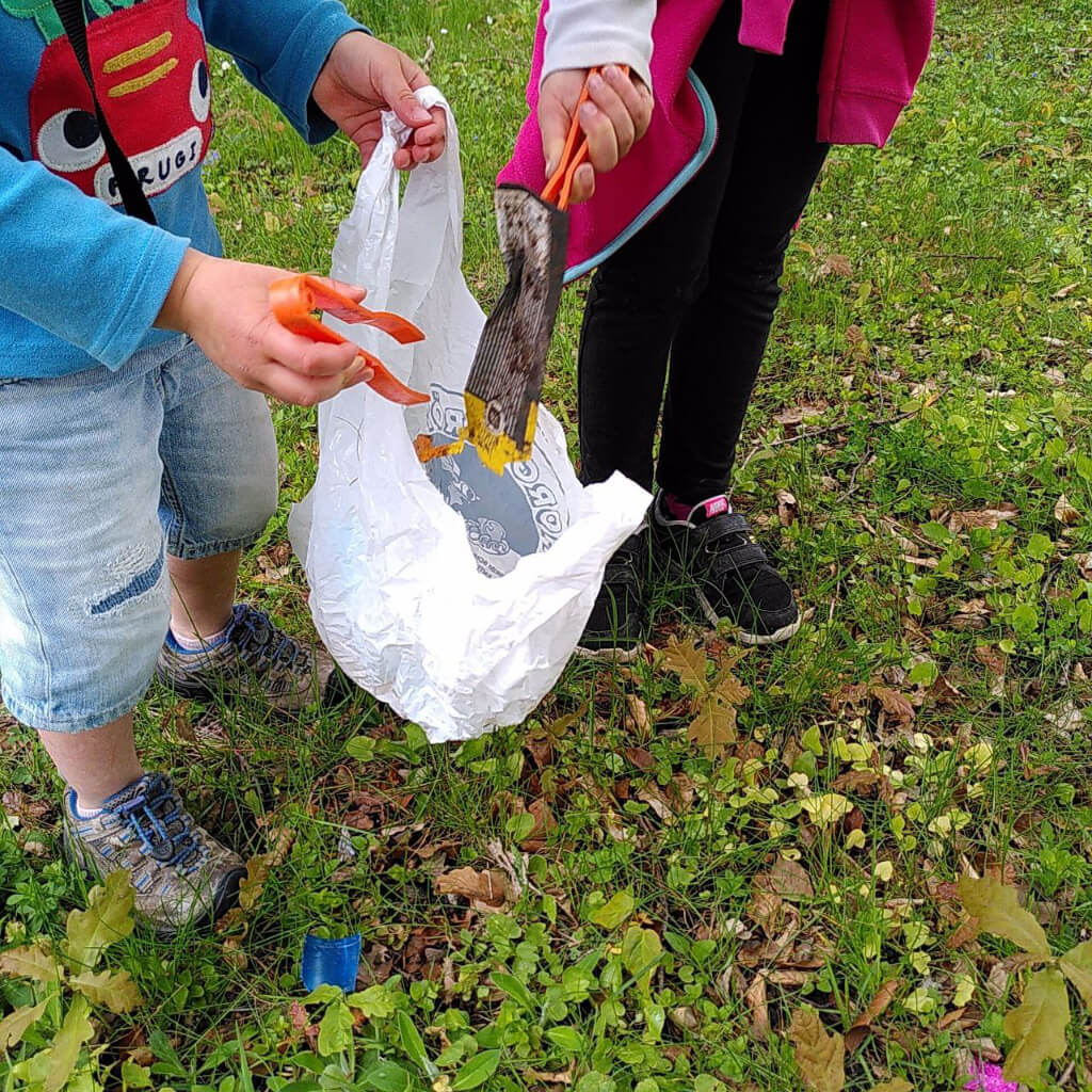 Kinder beim Müllaufsammeln auf einer Wiese